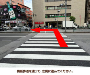 横断歩道を渡って、左側に進んでください。